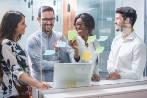 Creative group of business people brainstorming putting sticky notes on glass wall in office
