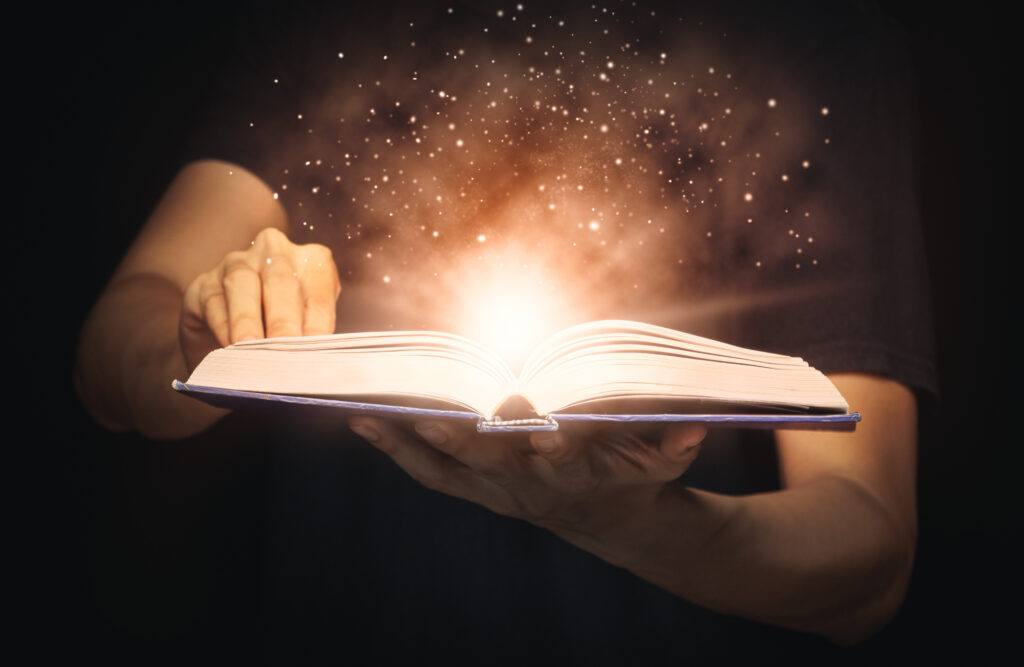 Man open magic book with growing lights and magic powder floating on the book
